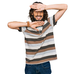 Young hispanic man wearing casual clothes smiling cheerful playing peek a boo with hands showing face. surprised and exited