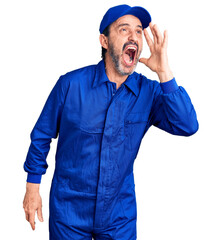 Canvas Print - Middle age handsome man wearing mechanic uniform shouting and screaming loud to side with hand on mouth. communication concept.