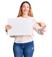 Sticker - Beautiful young woman holding blank empty banner smiling happy pointing with hand and finger