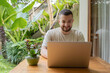 © Julija - Freelance concept. Young bearded man using laptop while sitting on summer terrace. Young male freelancer sitting outdoor working in laptop