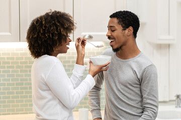 Wall Mural - Loving black woman feeding her handsome boyfriend, have breakfast together