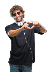 Sticker - Handsome hispanic man listening to music wearing headphones over isolated background smiling in love showing heart symbol and shape with hands. Romantic concept.