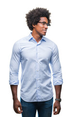 Wall Mural - Afro american business man wearing glasses over isolated background looking away to side with smile on face, natural expression. Laughing confident.