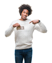 Poster - Afro american man holding one dollar over isolated background with surprise face pointing finger to himself