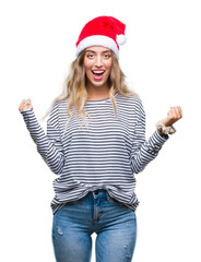 Poster - Beautiful young blonde woman wearing christmas hat over isolated background celebrating surprised and amazed for success with arms raised and open eyes. Winner concept.