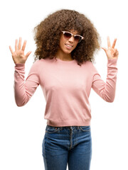 Poster - African american woman wearing pink sunglasses showing and pointing up with fingers number eight while smiling confident and happy.