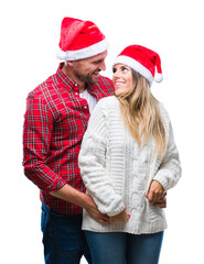 Sticker - Young couple in love wearing christmas hat over isolated background looking away to side with smile on face, natural expression. Laughing confident.