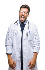 Wall Mural - Young handsome doctor man over isolated background sticking tongue out happy with funny expression. Emotion concept.