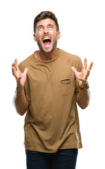 Canvas Print - Young handsome man over isolated background crazy and mad shouting and yelling with aggressive expression and arms raised. Frustration concept.