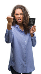 Wall Mural - Young hispanic woman holding passport of Italy annoyed and frustrated shouting with anger, crazy and yelling with raised hand, anger concept