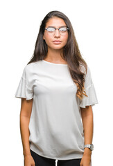 Wall Mural - Young beautiful arab woman wearing glasses over isolated background with serious expression on face. Simple and natural looking at the camera.