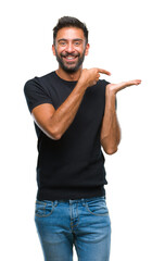 Canvas Print - Adult hispanic man over isolated background amazed and smiling to the camera while presenting with hand and pointing with finger.