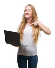 Sticker - Blonde teenager woman using computer laptop with surprise face pointing finger to himself