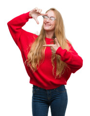 Sticker - Blonde teenager woman wearing red sweater smiling making frame with hands and fingers with happy face. Creativity and photography concept.