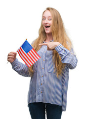 Canvas Print - Blonde teenager woman holding flag of United States of America very happy pointing with hand and finger