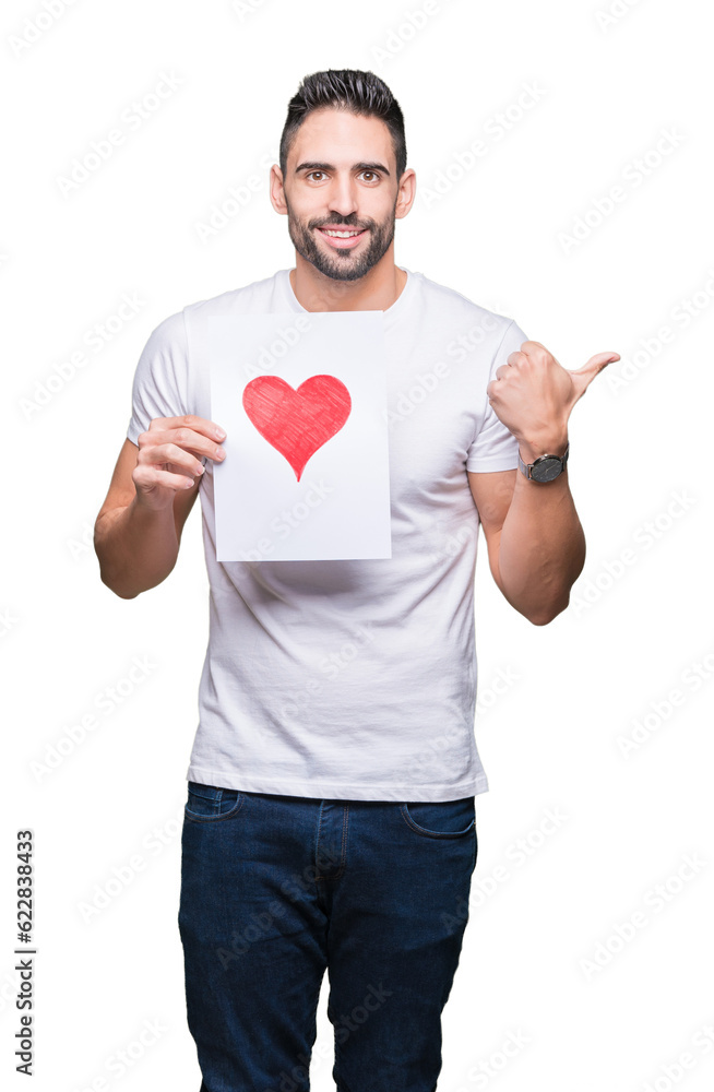Handsome young man holding card with red heart over isolated background pointing and showing with thumb up to the side with happy face smiling