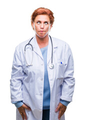 Sticker - Senior caucasian doctor woman wearing medical uniform over isolated background making fish face with lips, crazy and comical gesture. Funny expression.