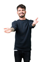 Sticker - Young handsome man over isolated background looking at the camera smiling with open arms for hug. Cheerful expression embracing happiness.