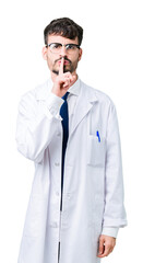 Poster - Young professional scientist man wearing white coat over isolated background asking to be quiet with finger on lips. Silence and secret concept.