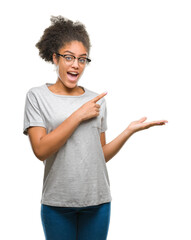 Sticker - Young afro american woman wearing glasses over isolated background amazed and smiling to the camera while presenting with hand and pointing with finger.