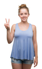 Wall Mural - Young blonde woman showing and pointing up with fingers number two while smiling confident and happy.