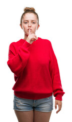 Sticker - Young blonde woman wearing bun and red sweater asking to be quiet with finger on lips. Silence and secret concept.