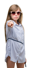 Sticker - Young blonde toddler wearing blue shirt pointing with finger to the camera and to you, hand sign, positive and confident gesture from the front