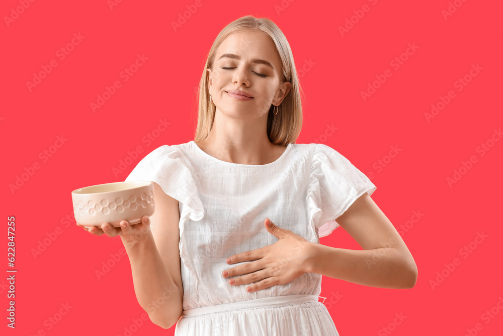 Young woman with bowl on red background