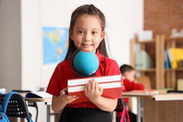 Poster - Little schoolgirl with books and globe in classroom