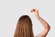 © Pixel-Shot - Young woman using cosmetic oil for hair treatment on light background, back view