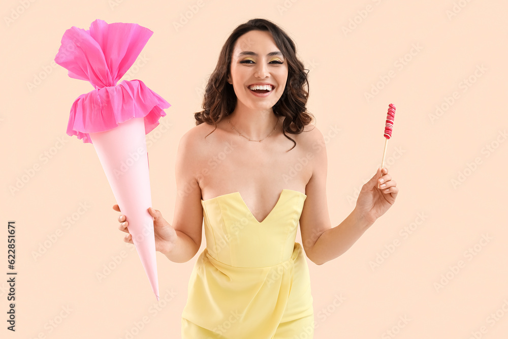 Young woman with lollipop and candy cone on beige background