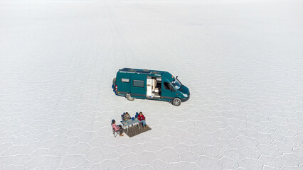 Poster - Aerial view of a family with their a 4x4 campervan in a huge salt flat doing picnic