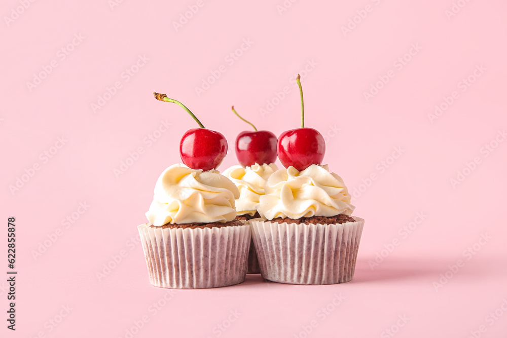 Tasty cherry cupcakes on pink background