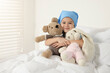 © New Africa - Childhood cancer. Girl hugging toy bunny and bear in hospital
