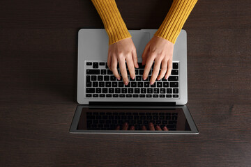 Wall Mural - Woman working with laptop at wooden table, top view