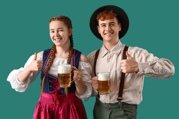 Young couple in traditional German clothes with beer on green background