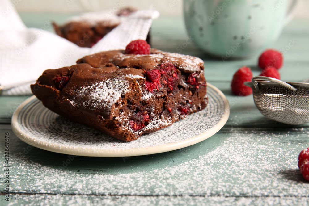 Plate with piece of raspberry chocolate brownie on blue wooden table
