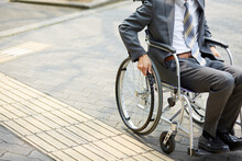 車椅子に乗るスーツ姿の男性と道路