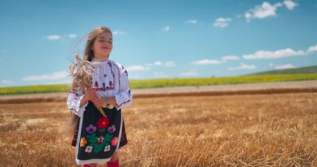 Wall Mural - Girl in traditional ethnic folklore costume with Bulgarian embroidery standing on a harvest golden wheat field, Bulgaria agriculture 4K video