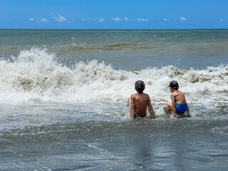 caucasian boys catching waves in the sea during storm. Children enjoys swimming in the ocean.