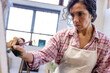 © Wavebreak Media - Biracial woman wearing apron painting on easel using brush in home studio