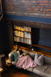 © Wavebreak Media - Biracial woman sitting on sofa reading book in living room, copy space