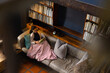 © Wavebreak Media - Biracial woman sitting on sofa reading book in living room, copy space