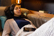 © Wavebreak Media - Biracial woman lying on sofa wearing headphones in living room