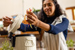 © Wavebreak Media - Happy biracial woman wearing apron cleaning waste in kitchen