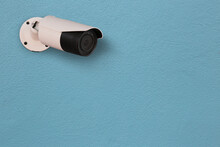 White CCTV Camera System Mounted On Light Blue Wall Of Blue Cement Wall.