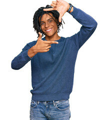 Wall Mural - Young african american man wearing casual winter sweater smiling making frame with hands and fingers with happy face. creativity and photography concept.