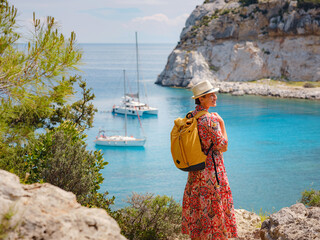 Wall Mural - Asian woman in hat look on views of azure Bay in Mediterranean sea. Travel and vacation concept. Anthony Quinn bay with crystal clear water in Rhodes island, Greece. The most beautiful beach.