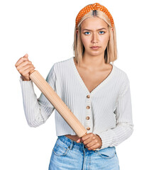 Poster - Beautiful young blonde woman holding kneading roll relaxed with serious expression on face. simple and natural looking at the camera.