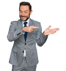 Poster - Middle age man wearing business clothes amazed and smiling to the camera while presenting with hand and pointing with finger.